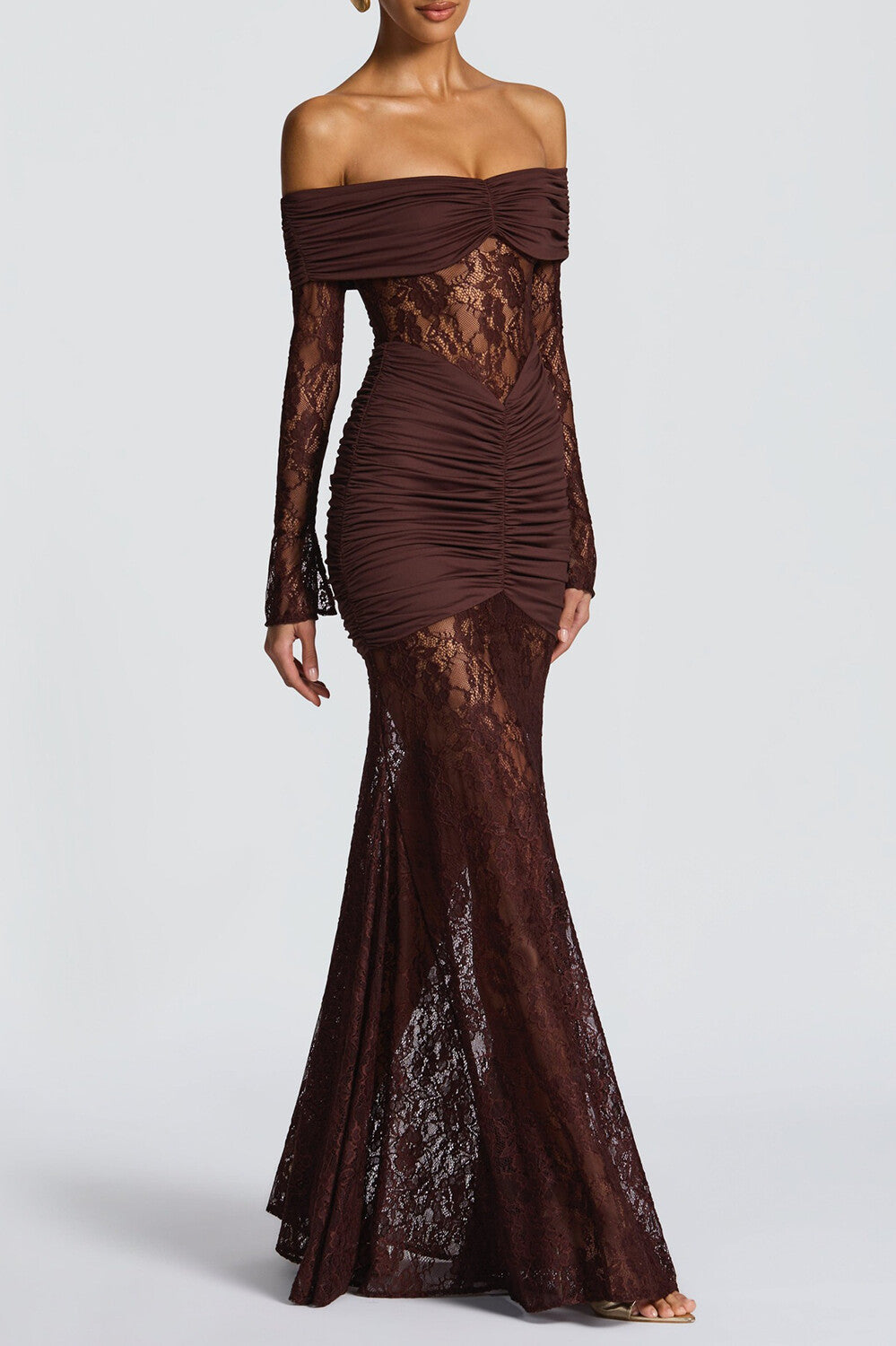 Woman wearing a dark brown off-the-shoulder formal dress with long lace sleeves and ruched detailing.