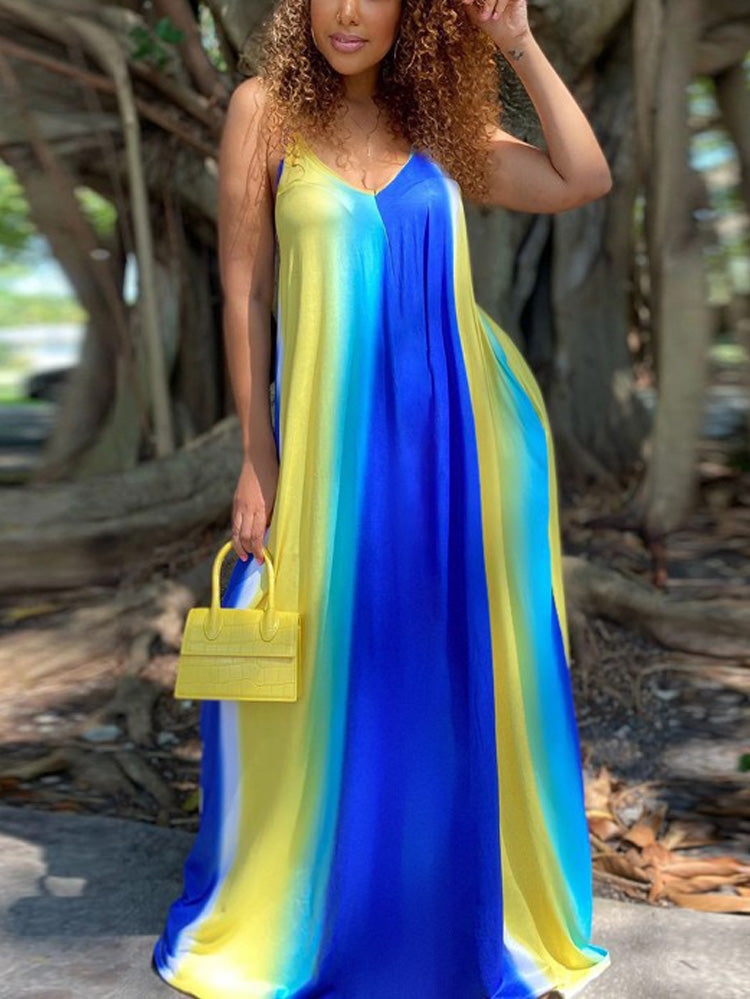 Woman with curly hair wearing a blue, yellow, and white tie-dye maxi dress and a yellow handbag, standing outdoors.