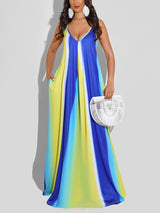 Woman wearing a blue, yellow, and white tie-dye maxi dress with spaghetti straps and pockets, holding a white woven bag.