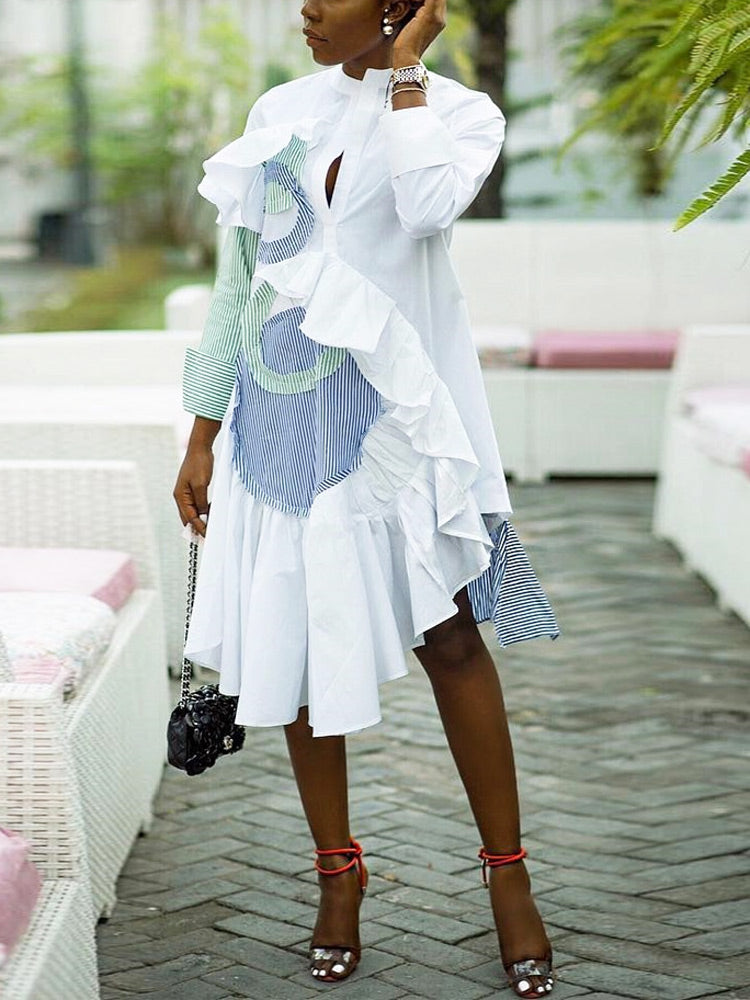 woman wearing a white shirt dress with green and blue stripe accents and ruffles