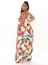 Side view of a plus-size woman in a cream-colored tropical print maxi dress with a V-neck and crochet trim.