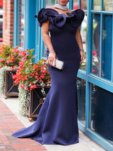 Full-length view of a woman in a navy blue mermaid gown with a ruffled neckline.