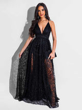 Woman in a black floor-length gown with spaghetti straps and a deep V-neckline standing with one hand on her hip.