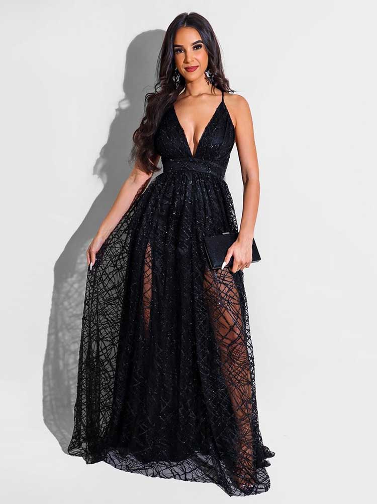 Woman in a black floor-length gown with spaghetti straps and a deep V-neckline standing with one hand on her hip.