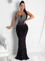 Woman wearing a black embellished formal gown with a plunging neckline and spaghetti straps.