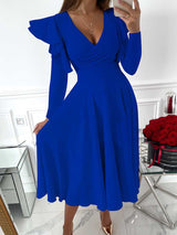 woman wearing a royal blue V-neck dress with ruffled long sleeves and a flared skirt