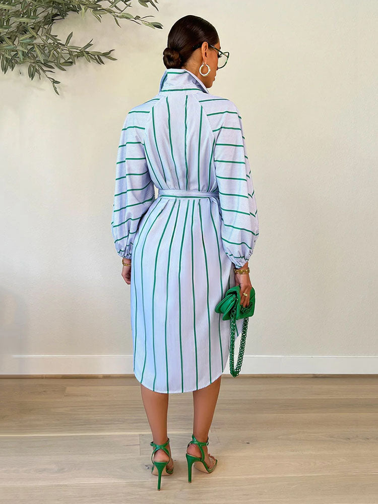 Back view of a woman wearing a light blue and green striped shirt dress with a belted waist and balloon sleeves.