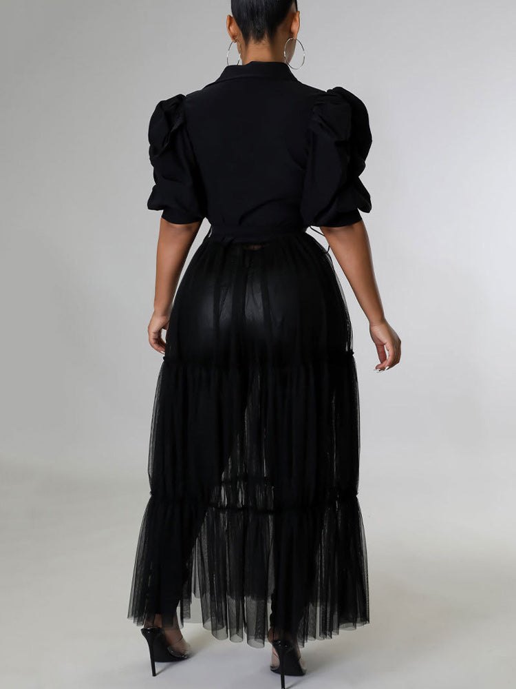 Back view of a woman wearing a black maxi dress with puffed sleeves and a tiered tulle skirt over black pants