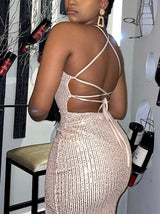Back view of a woman in a rose gold sequined evening gown with criss-cross straps.