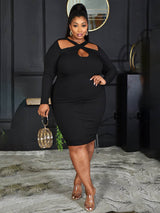 Woman wearing a black long-sleeved ribbed knit bodycon dress with a cutout neckline and a gold clutch bag.
