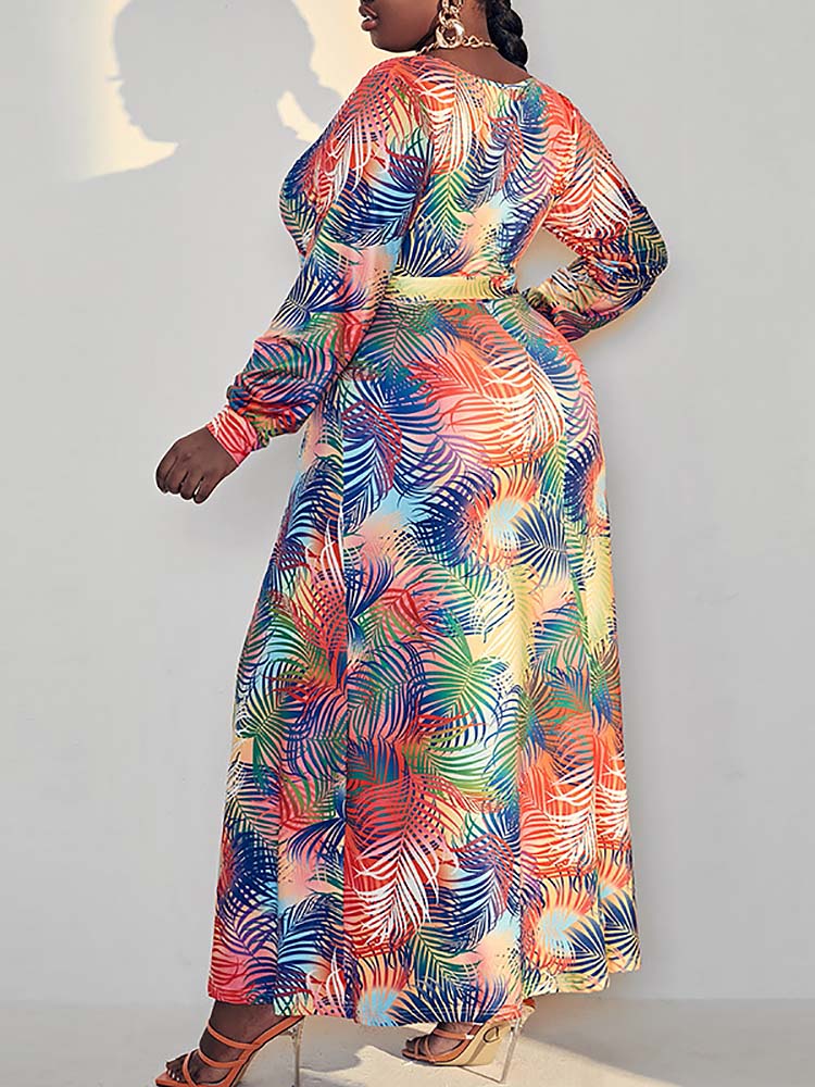 Rear view of a woman in a tropical print maxi dress, highlighting the back of the garment and the all-over pattern.