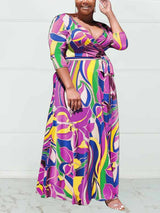 Side view of a woman in a purple and yellow floral print wrap maxi dress.