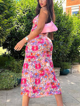 Back view of a woman wearing a floral print midi dress with a high slit.