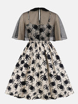 back view of a cream A-line dress with a black spider print and a black mesh capelet overlay