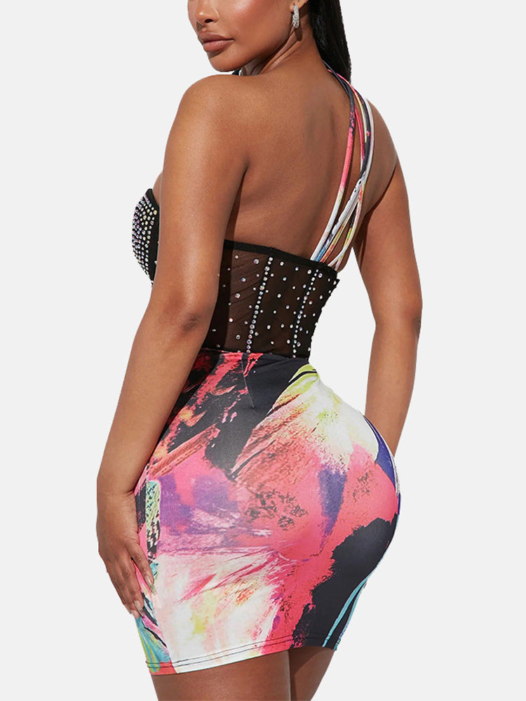 Back view of a woman wearing a black mesh dress with rhinestone embellishments and colorful abstract print skirt