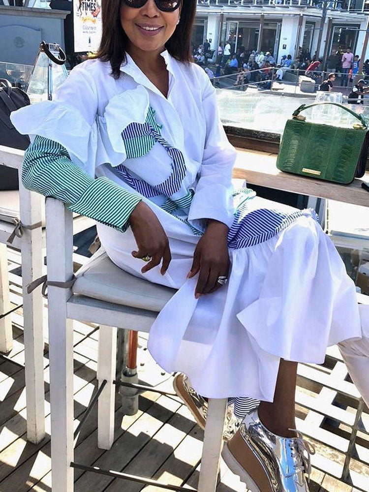woman sitting outdoors in a white shirt dress with contrasting stripes and ruffles