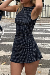 Woman posing in a navy polka dot mini dress on a street.