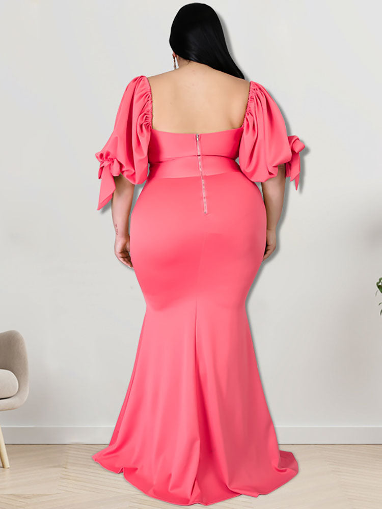 Back view of a woman in a coral mermaid gown with puffed sleeves and a zipper closure