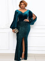 Woman wearing a long, teal velvet dress with sequined skirt and bishop sleeves, standing in front of a white wall.