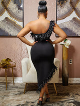 Back view of a woman wearing a black one-shoulder dress with feather trim and asymmetrical hemline.