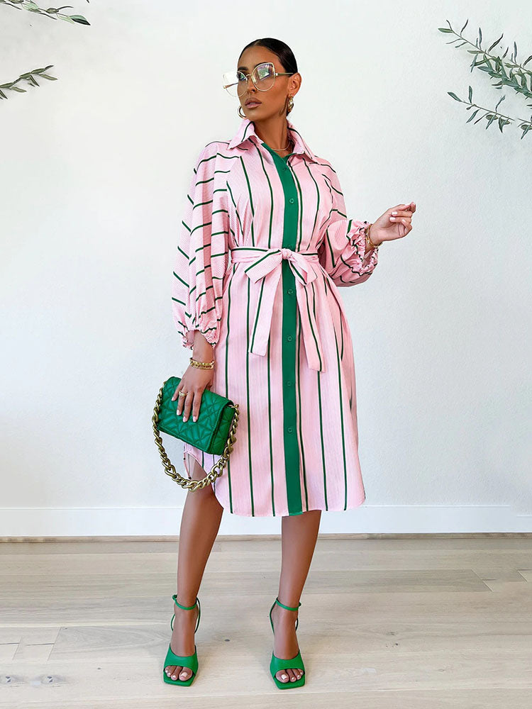 Woman wearing a pink and green striped shirt dress with a belted waist and balloon sleeves.