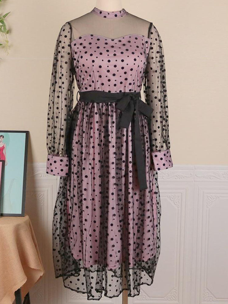 Pink and black polka dot midi dress with sheer long sleeves and a black ribbon belt, displayed on a mannequin.