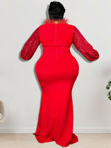 Back view of a woman wearing a red sequined top with long sleeves and a red floor-length mermaid skirt, featuring red feather trim around the neckline.