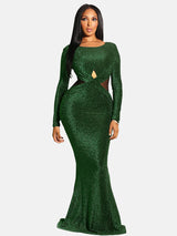 Woman in a green sparkly long-sleeved mermaid gown with cutout details.
