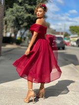 Back view of a woman in a red off-the-shoulder dress with a flared skirt, showcasing the back detail.