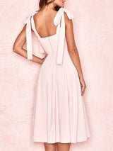 A pink midi dress with tie shoulder straps and a ruched sweetheart neckline, displayed against a white background.