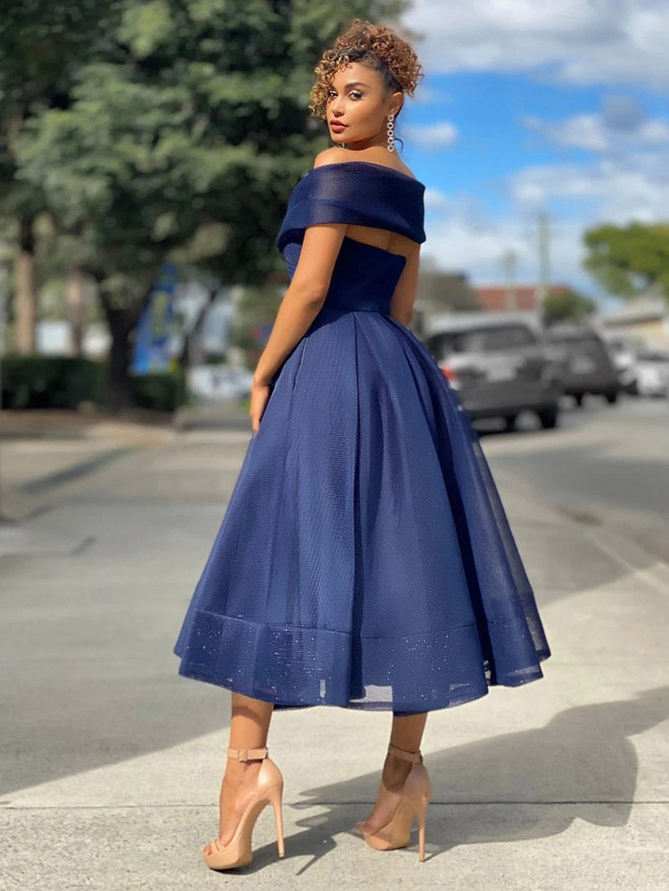 Back view of a woman in a navy blue off-the-shoulder dress with a flared skirt, showcasing the back detail.