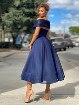 Back view of a woman in a navy blue off-the-shoulder dress with a flared skirt, showcasing the back detail.