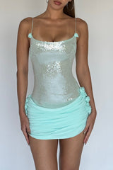 Woman wearing a light blue sequined mini dress with ruched skirt and floral accents