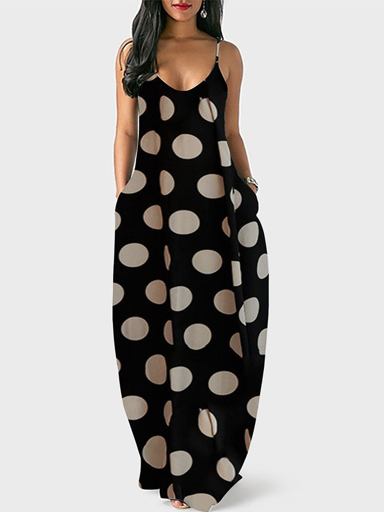Woman wearing a black polka dot maxi dress with spaghetti straps and pockets, front view