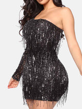 Close-up of a woman wearing a black sequined one-shoulder mini dress with fringe details