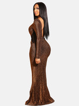 Side view of a woman in a bronze sparkly long-sleeved mermaid gown, showing the open back.