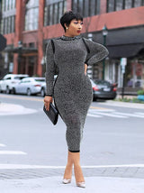 Woman wearing a black rhinestone midi dress and holding a black clutch.