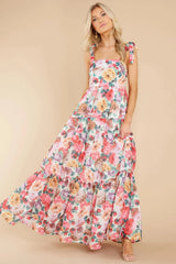 Close-up of the floral pattern and tiered design of a maxi dress worn by a woman.