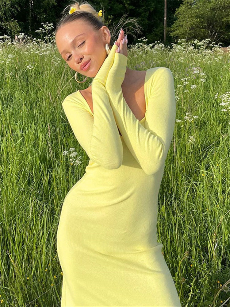 Close-up of a woman in a yellow ribbed knit maxi dress with long sleeves and a sweetheart neckline.