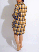 Back view of a woman wearing a yellow and blue plaid shirt dress with thigh-high boots.