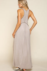 back view of a woman in a grey sleeveless maxi dress with a zipper closure and decorative trim