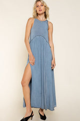 woman wearing a blue sleeveless maxi dress with a high side slit and a decorative neckline trim