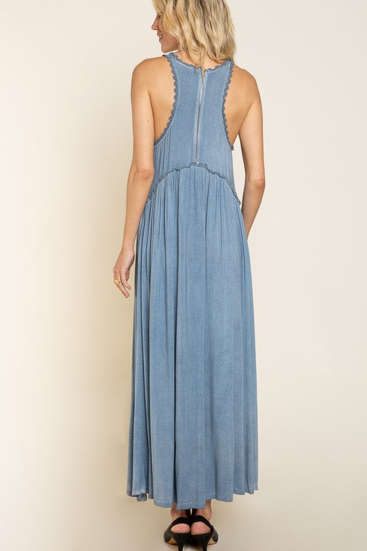 back view of a woman in a blue sleeveless maxi dress with a zipper closure and decorative trim