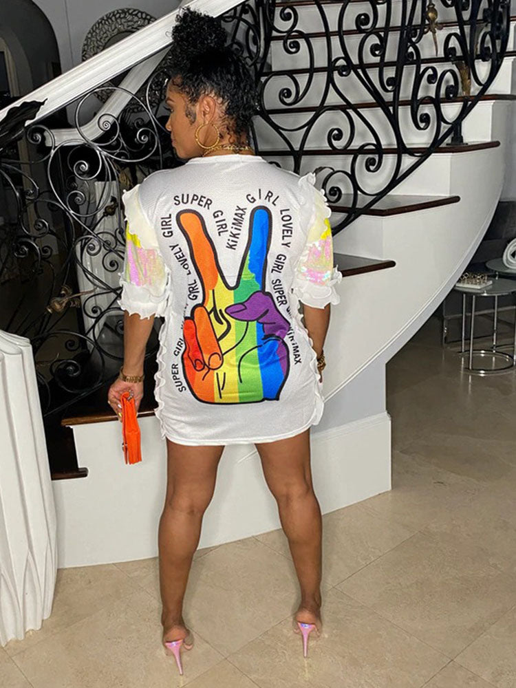 Back view of a woman wearing a white sequined t-shirt dress with a rainbow peace sign graphic and text.