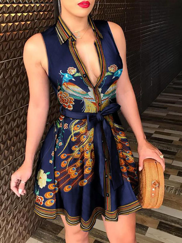 Woman wearing a sleeveless V-neck mini dress with a peacock print and tie waist.