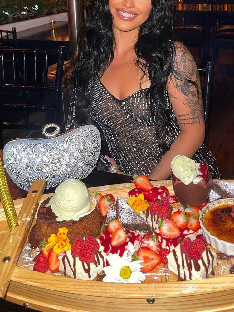 Woman in a black embellished dress sitting at a table with a dessert platter.