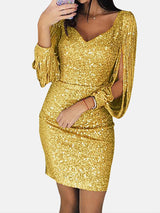 Woman wearing a gold sequin dress with tassel sleeves