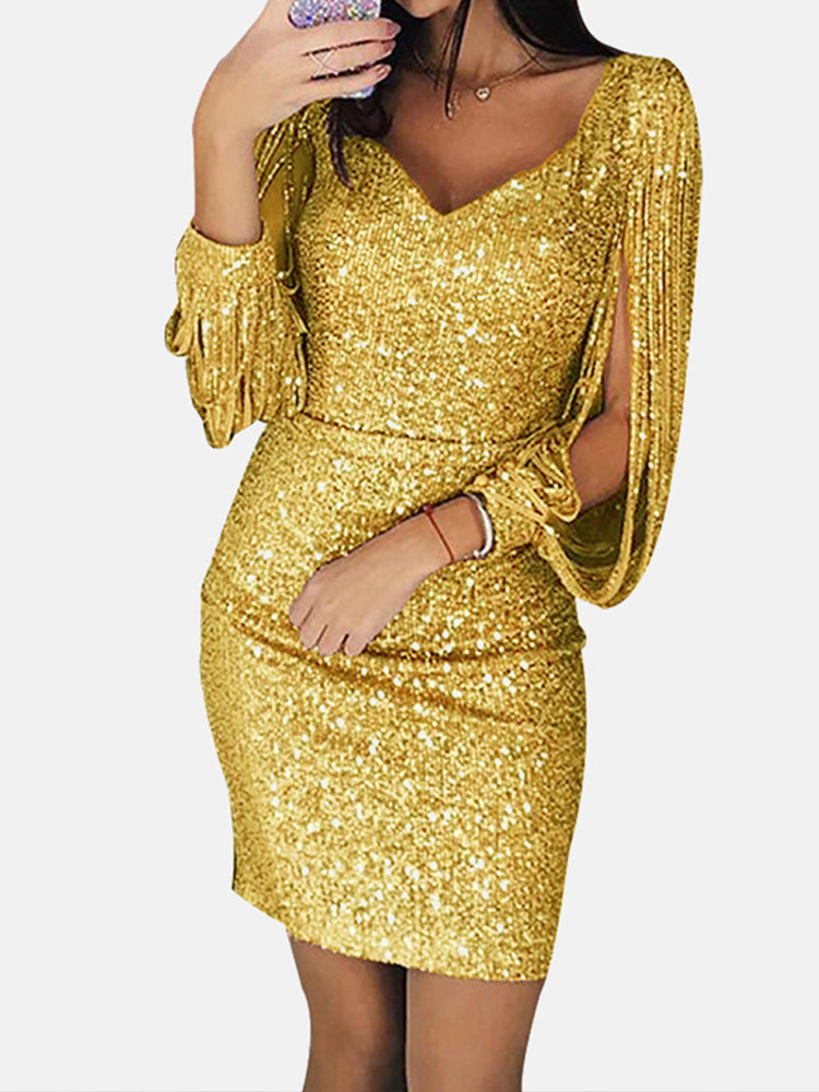 Woman wearing a gold sequin dress with tassel sleeves