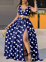 Woman wearing a navy blue maxi dress with white polka dots and a gold belt.