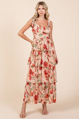 Woman wearing a blush pink floral print tiered maxi dress with tie shoulder straps